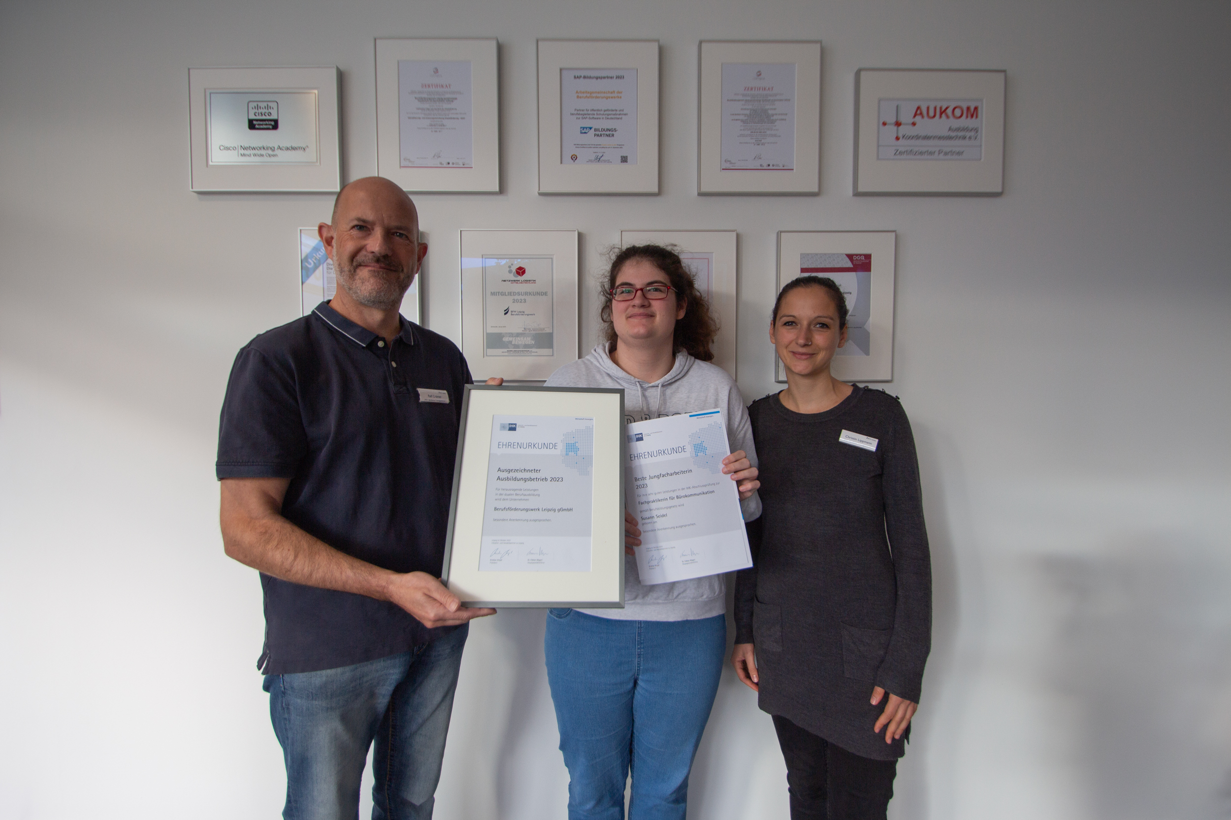 Gruppenfoto der besten Jungfacharbeiterin 2023, Ausbilder und Sozialpädagogin aus dem BTZ am BFW in Leipzig präsentierten die Urkunden: Ausgezeichneter Ausbildungsbetrieb 2023 und Beste Jungfacharbeiterin 2023.